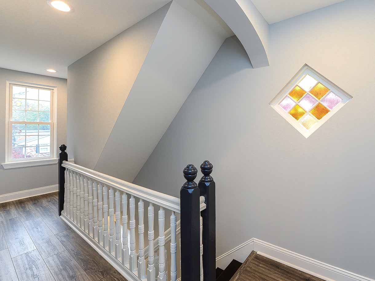 Inside view of a staircase in a house designed by Goldleaf, with stained glass window and modern details