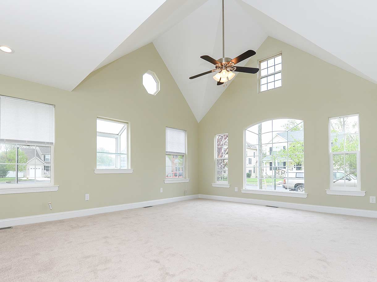 Large, beige living room with large windows designed by Goldleaf