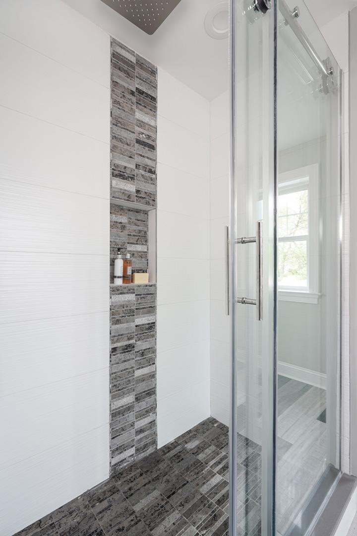 Bright, modern bathroom with multi-colored grey flooring, stand alone bathtub, and shower